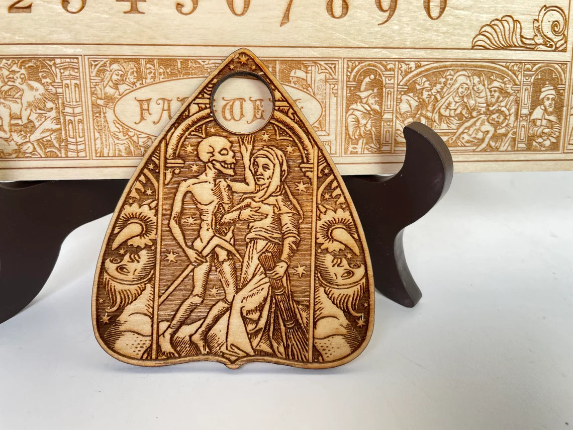 Close up of engraved medieval Danse Macabre imagery on wooden spirit board
