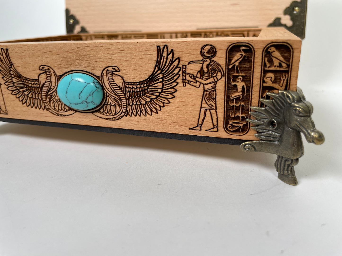 Wooden box with Egyptian-themed engraving and turquoise stone on a white background