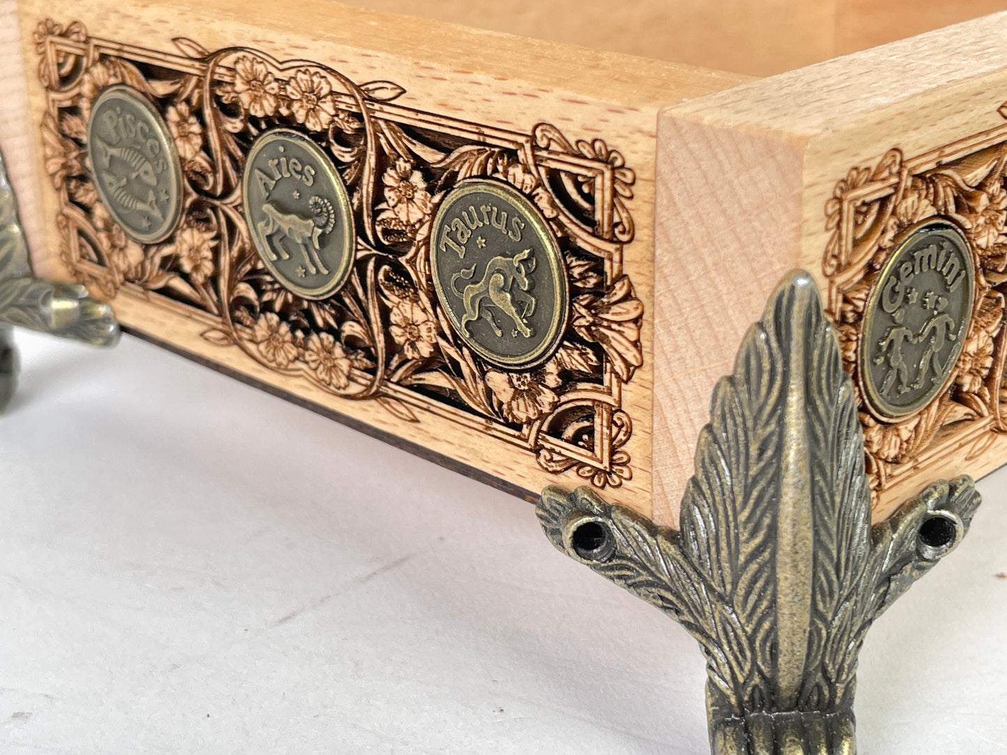 Decorative wooden box with metal accents and engraved symbols on a white surface.