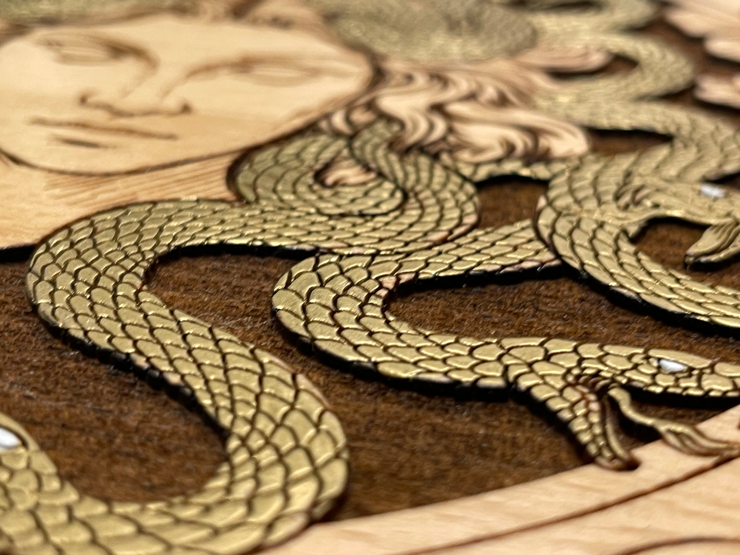 Close up of engraved Medusa art on wooden tarot deck storage box
