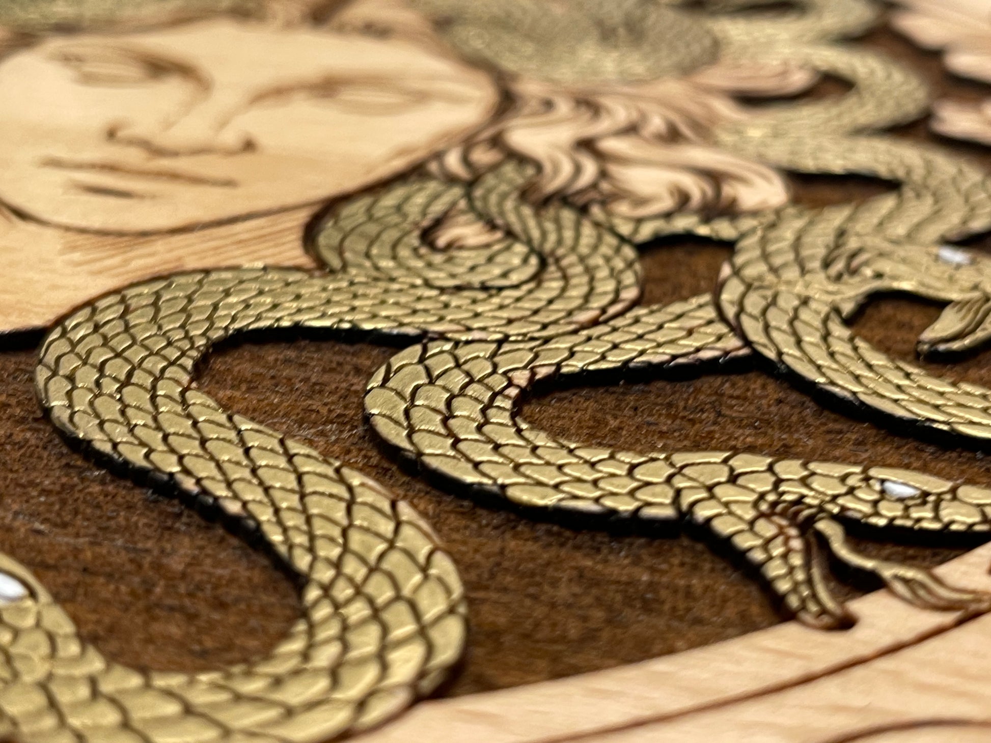 Close up of engraved Medusa art on wooden tarot deck storage box
