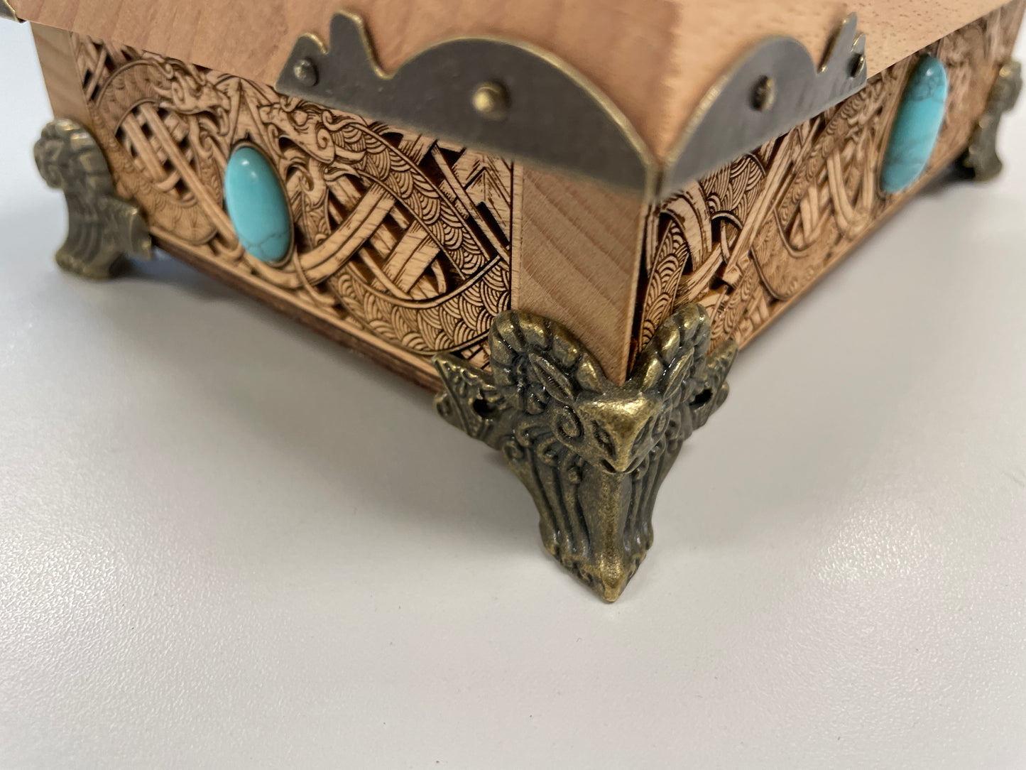 Decorative Viking  wooden box with intricate carvings and turquoise stones on a white background