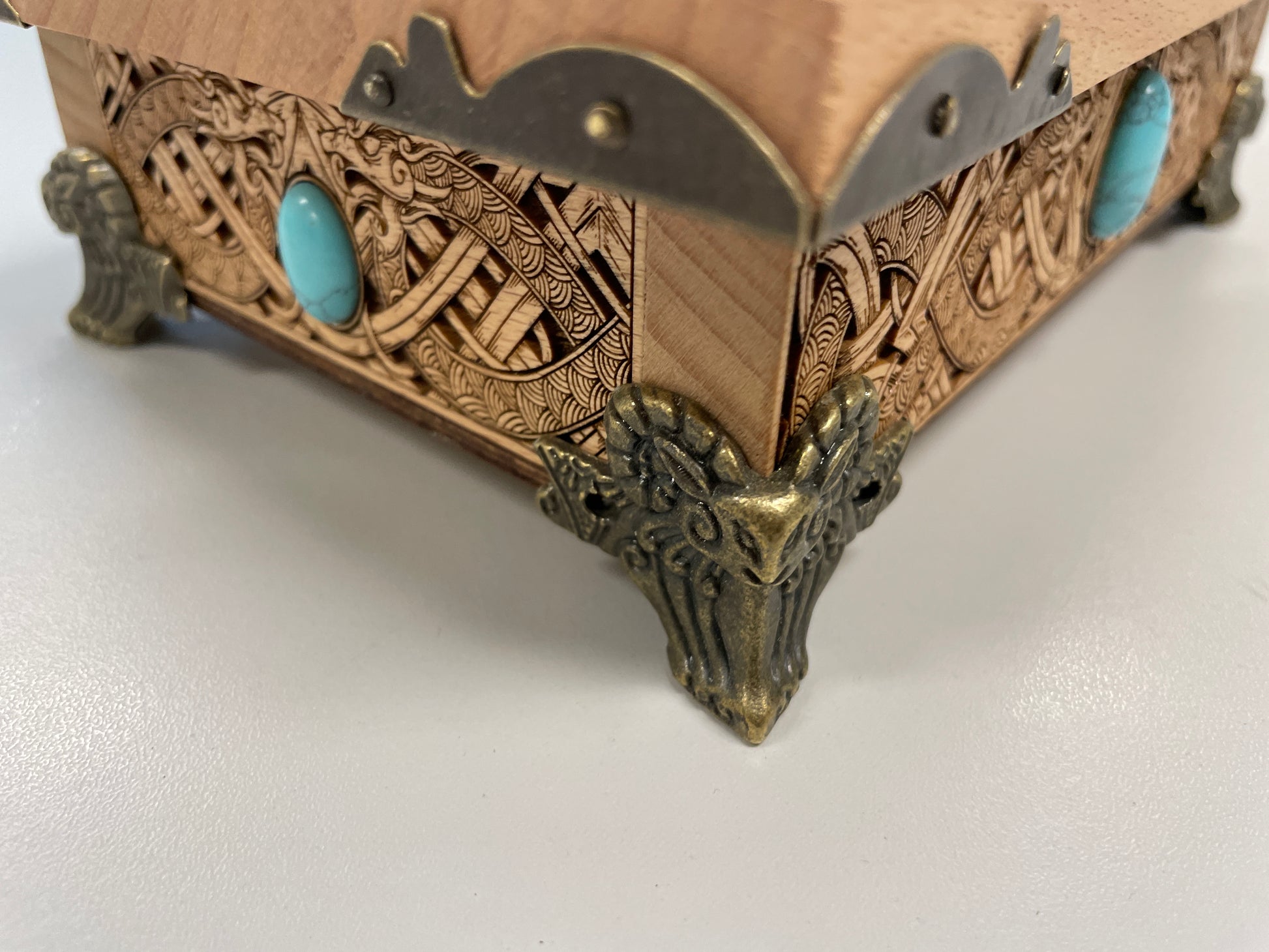 Decorative Viking  wooden box with intricate carvings and turquoise stones on a white background