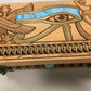 Close-up of Eye of Horus engraving on wooden Egyptian tarot box, winged Horus motif with blue turquoise inlay