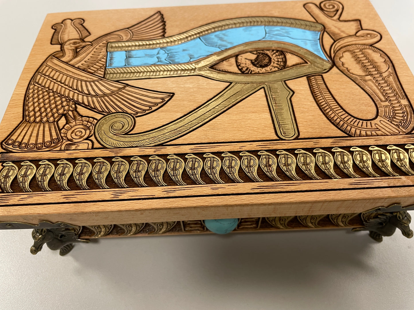 Close-up of Eye of Horus engraving on wooden Egyptian tarot box, winged Horus motif with blue turquoise inlay