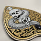 Decorative ouija board planchette with snake and skull design on an ornate shield-shaped background