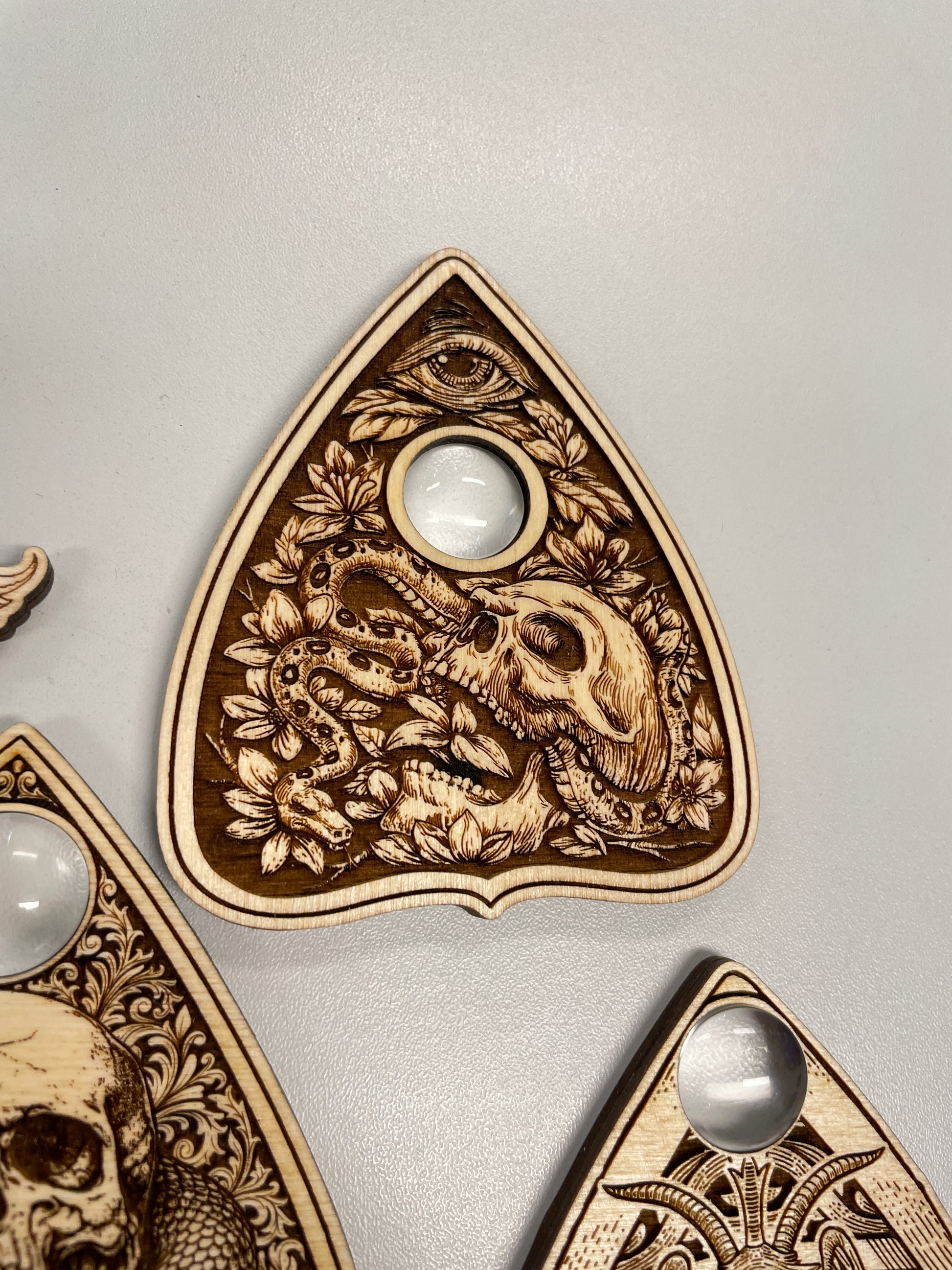 close up engraved ouija planchette skull snake design wooden spirit board tool