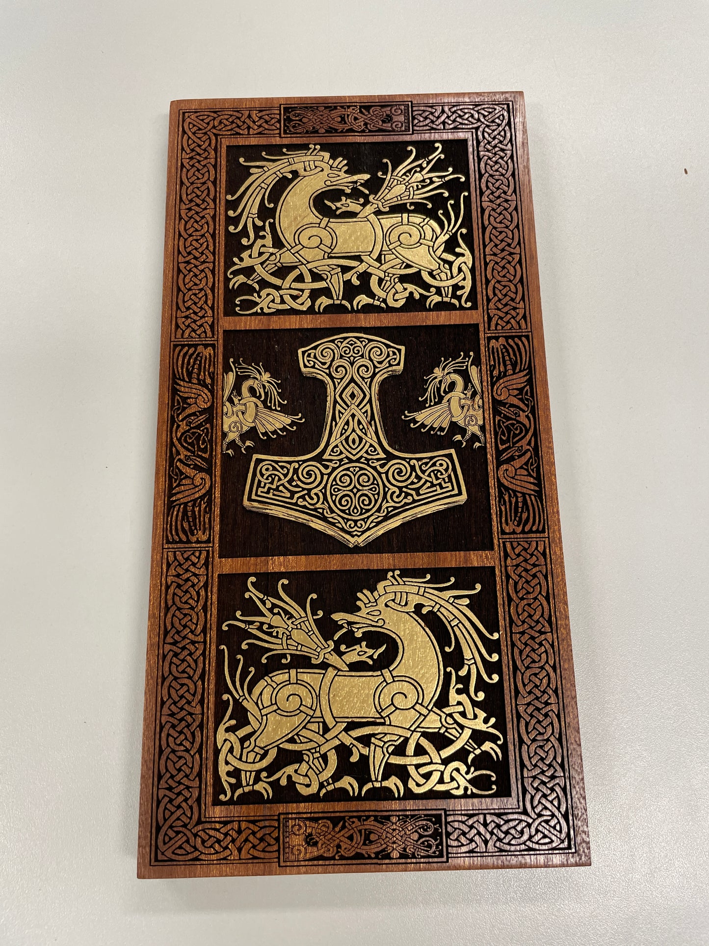 Decorative panel with Celtic designs and a central Thor hammer symbol on a white background