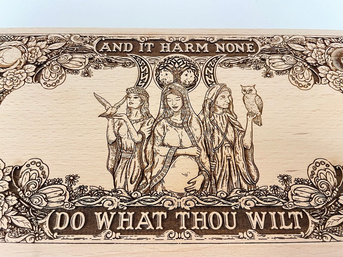 Close up of Triple Moon engraving with Wiccan oath on wooden altar board
